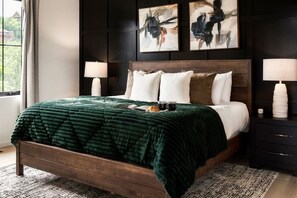 A bed with a dark green blanket, two bedside lamps, and two abstract paintings on the wall. - SwimSpa/HotTub/GameRoom/FirePit&Yard/Peloton/LUXE (Gatlinburg)
