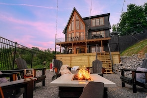 Eine zweistöckige Lodge mit Feuerstelle und Sitzgelegenheiten im Freien.