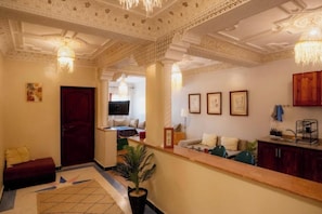 Um saguão de hotel com balcão de recepção, área de estar e teto decorativo.