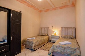 Ein Schlafzimmer mit zwei Betten, einem Kleiderschrank und einem Nachttisch mit Lampe.