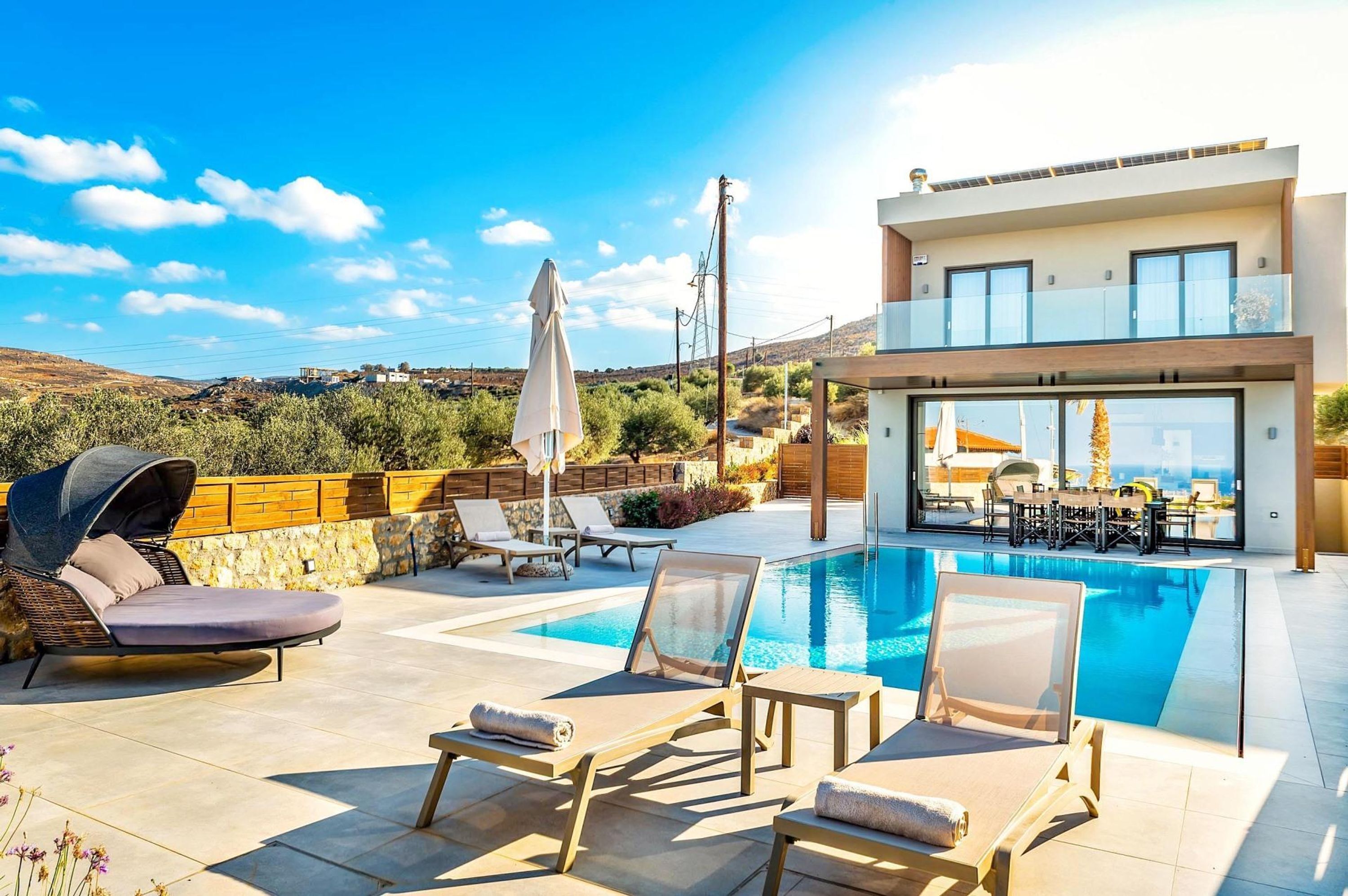 A modern villa with a pool, outdoor seating, and a view of the landscape.