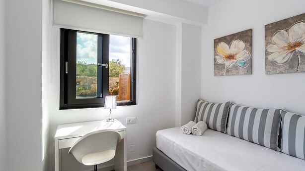 Un dormitorio con cama, escritorio y ventana.
