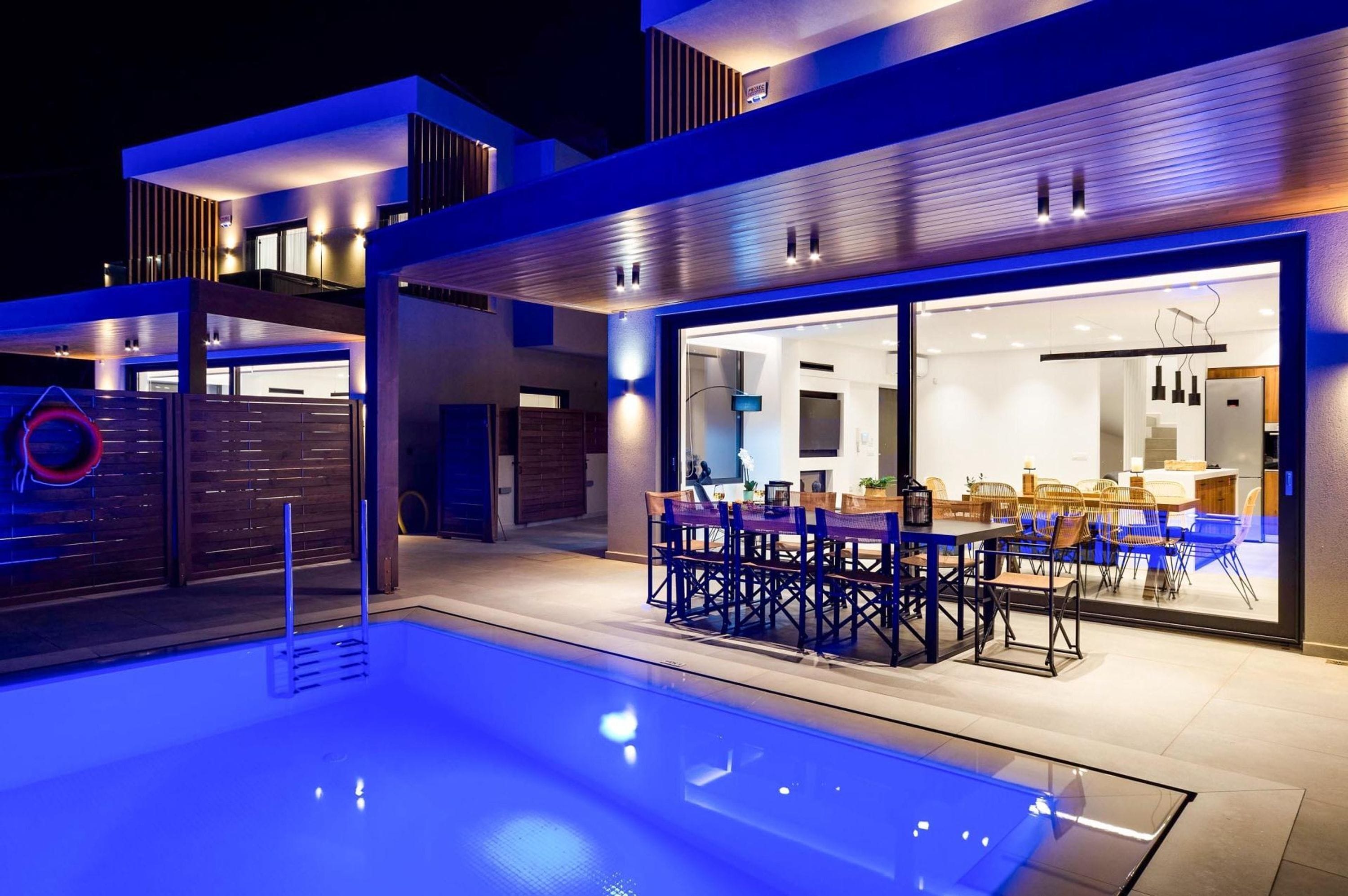 A modern outdoor pool area with a dining setup.