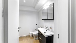 A modern bathroom with a white sink, mirror, and toilet. - Kamelia Luxury Villa 2 (Hersonissos)
