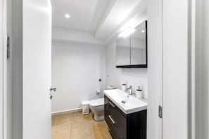 Ein modernes Badezimmer mit Waschbecken, Spiegel und Toilette in Weiß.