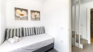 A bedroom with a bed, pillows, and two wall-mounted flower paintings. - Kamelia Luxury Villa 2 (Hersonissos)