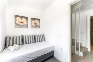 Ein Schlafzimmer mit einem Bett, Kissen und zwei an der Wand hängenden Blumenbildern.