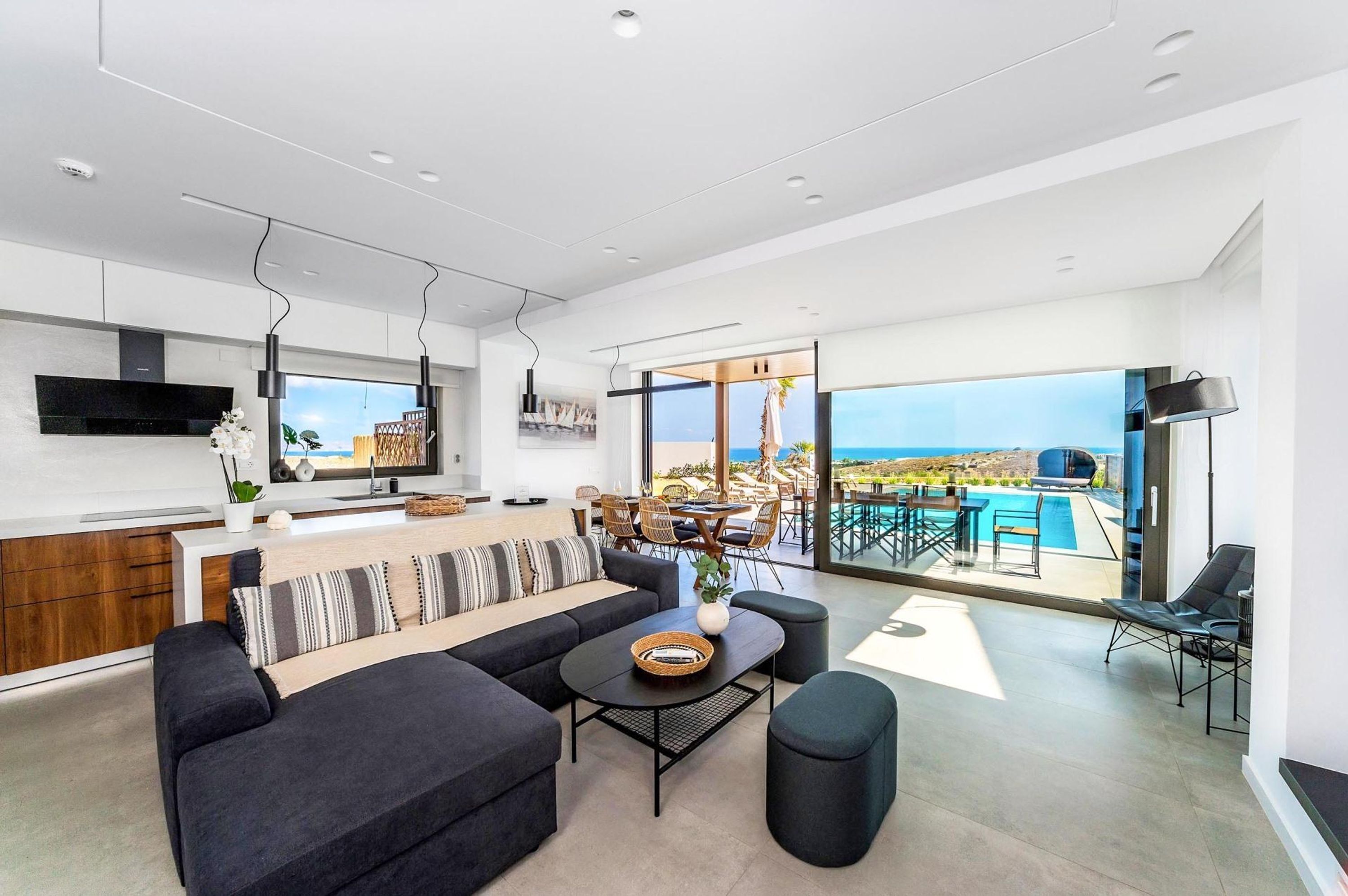 Un espace de vie moderne comprenant une cuisine, un coin repas et un balcon avec vue sur la piscine.