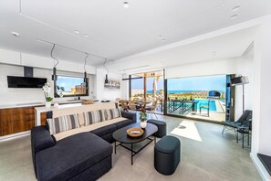 A modern living space with a kitchen, dining area, and a balcony with a pool view.