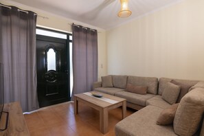 A living room with a sofa, a coffee table, and a door with curtains. - Villa Melody in Zakynthos (Zakynthos)