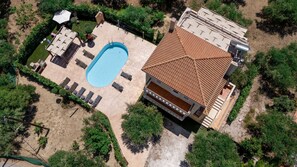 An aerial view of a residential property with a swimming pool, sun loungers, a covered patio, and a house with a tiled roof. - Villa Melody in Zakynthos (Zakynthos)