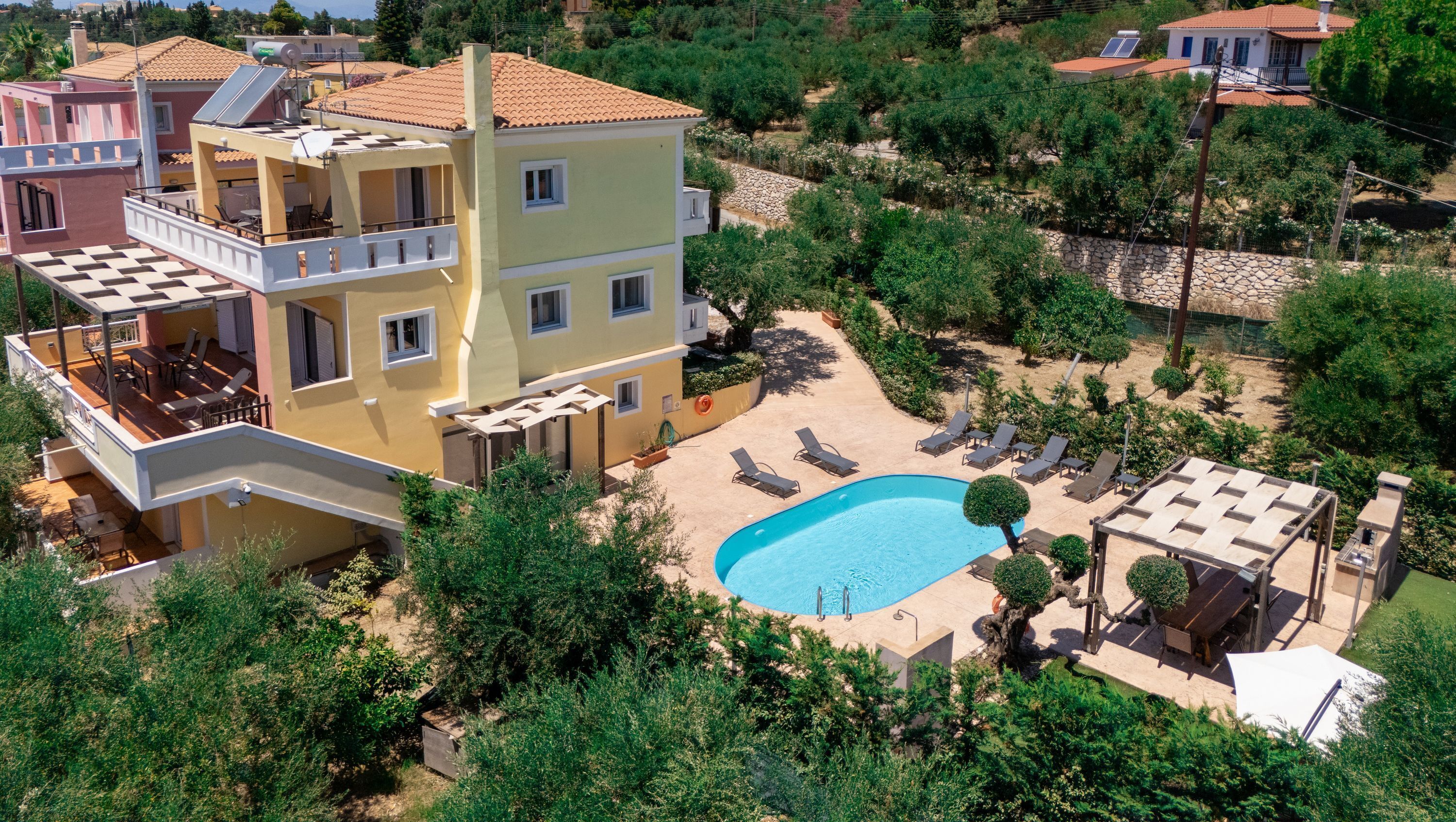 Un edifici de diversos pisos amb piscina, zona d'estar a l'aire lliure i jardí.