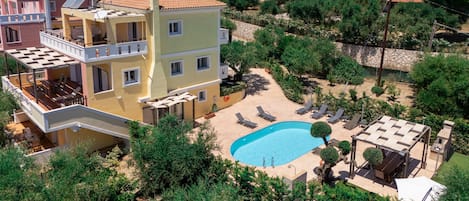 A multi-story building with a swimming pool, outdoor seating, and a garden.