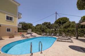 A swimming pool with lounge chairs and a building in the background. - Villa Melody in Zakynthos (Zakynthos)