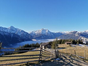 A mountain landscape with a wooden cabin and a fenced area.