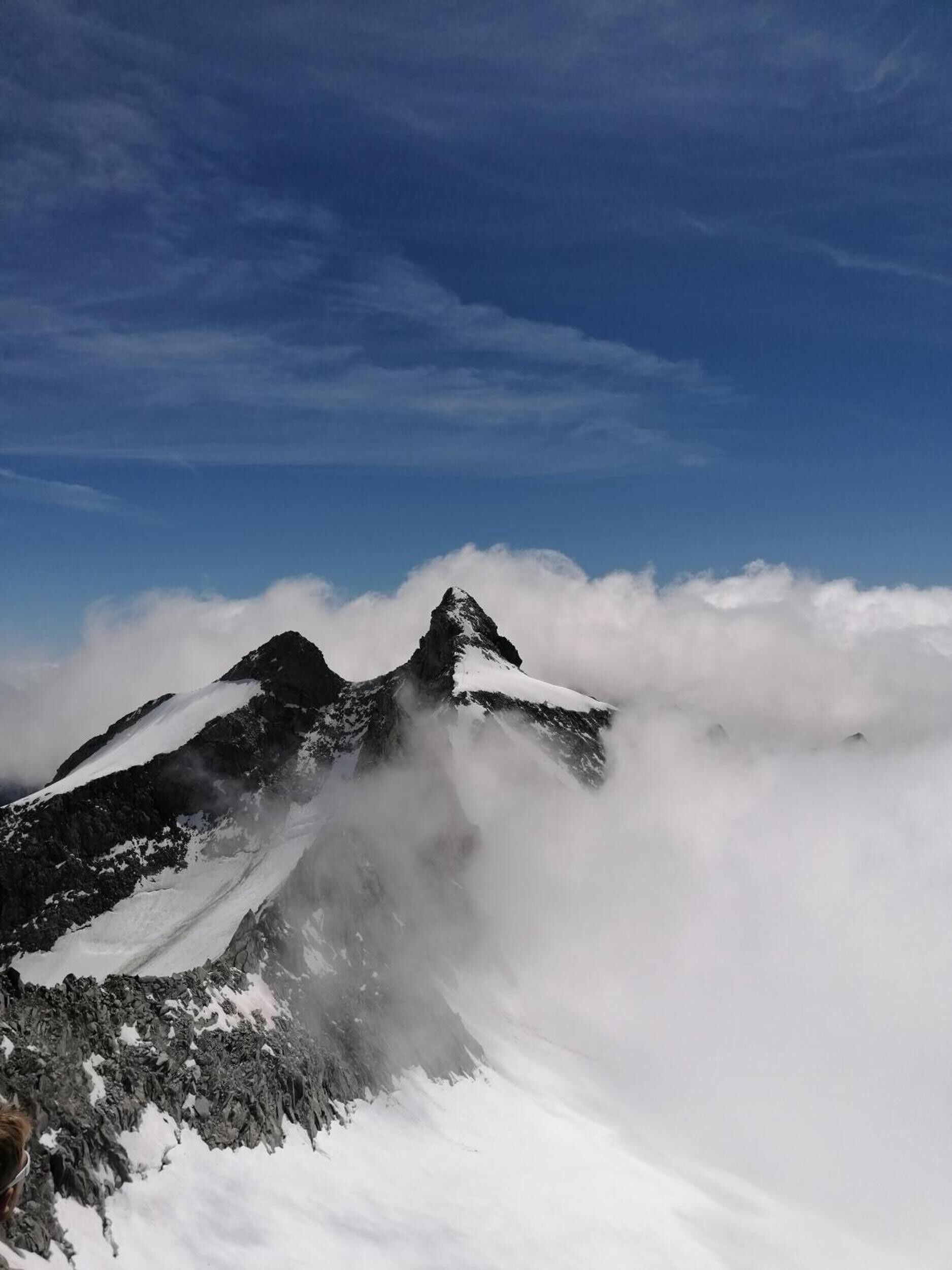A mountain peak with snow-covered slopes and a clear sky above.