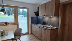 Eine moderne Küche mit Holzausstattung, einer schwarzen Arbeitsplatte und einem Fenster mit Blick ins Freie.