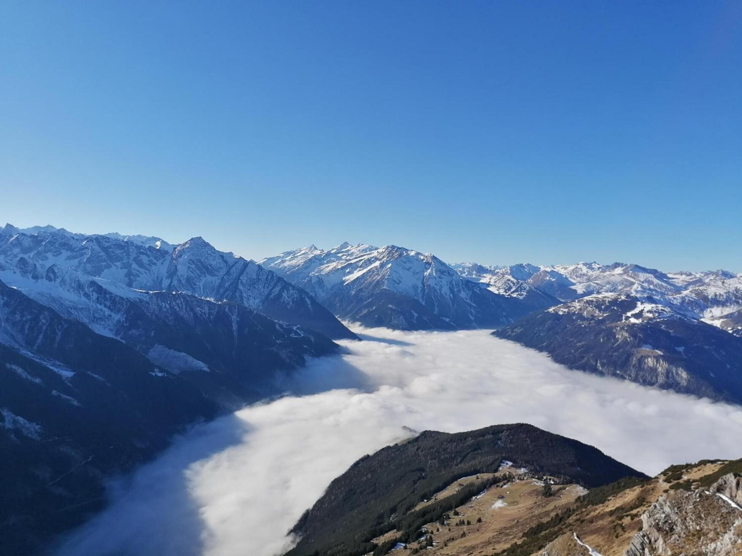 A mountain landscape with snow-capped peaks and a valley below.