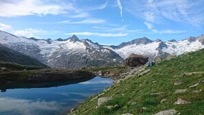 Paisaje de montaña con un lago cristalino, terreno rocoso y un grupo de excursionistas.