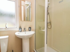Ein Badezimmer mit einem weißen Waschbecken, einem Spiegel darüber und einer Duschkabine.