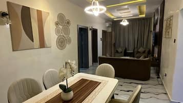 A modern living room with a sofa, a dining table with chairs, and a decorative wall piece.