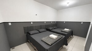 A room with two beds, each with a pillow and a blanket. - Aconchego de Lugar - Eri & Douglas - 3 (Belo Horizonte)