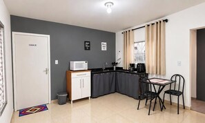 Una cocina funcional con microondas, pileta y un pequeño comedor con sillas.