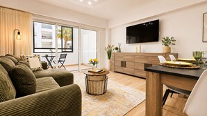 Een moderne woonkamer met een bank, een salontafel en een eethoek met een tafel gedekt voor twee personen.