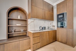 A modern kitchen with wooden cabinetry, a marble countertop, and a built-in oven. - Superbe Apartment Saint Honoré Elysée Palace (Paris)