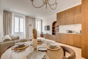 A modern living room with a dining area, wooden cabinets, and a kitchen with marble countertops. - Superbe Apartment Saint Honoré Elysée Palace (Paris)