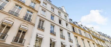 A multi-story building with multiple windows and balconies, featuring a prominent Chanel store on the ground floor.