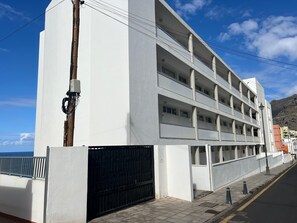 Ein mehrstöckiges Gebäude mit Balkonen, einem verschlossenen Eingang und freiem Blick auf das Meer.