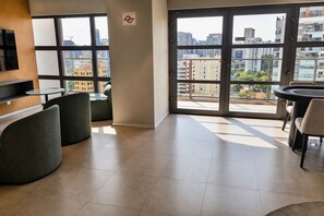 A modern interior with a large window, a seating area, and a flat-screen TV. - Luxury apartment on the 25th floor with parking space and close to the Brooklyn Metro station. (São Paulo)