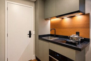 Eine moderne Küche mit eingebautem Backofen, Spüle aus Edelstahl und einer Holzrückwand.