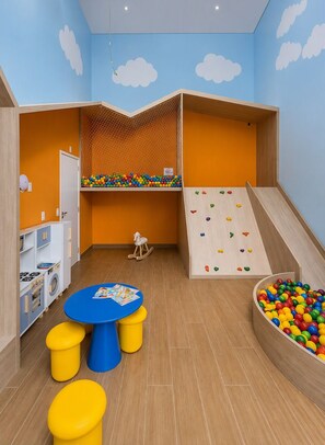 Ein Kinderspielbereich mit Kletterwand, Bällebad und Spielküche.