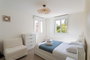 A bedroom with a bed, a chair, a dresser, and two windows. - Pieta - À moins de 100 m du port (Cancale)