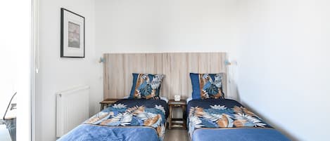Un dormitorio con dos camas, cabecero de madera, un cuadro en la pared y una ventana a la izquierda.