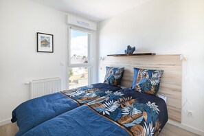 Ein Schlafzimmer mit einem Bett, einem Heizkörper, einem Fenster und einem Bild an der Wand.