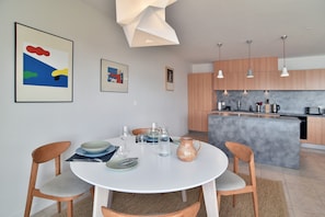 A modern kitchen with wooden cabinets, a central island, and pendant lighting. - Ciel & Mer - Avec vue imprenable sur la mer (Saint-Malo)