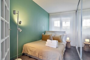 Un dormitorio con cama, mesitas de noche, un espejo y una ventana con cortinas.