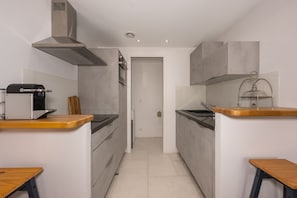 A compact kitchen with a microwave, stove, and ventilation hood. - Le Charme - Studio avec Parking (Janvry)