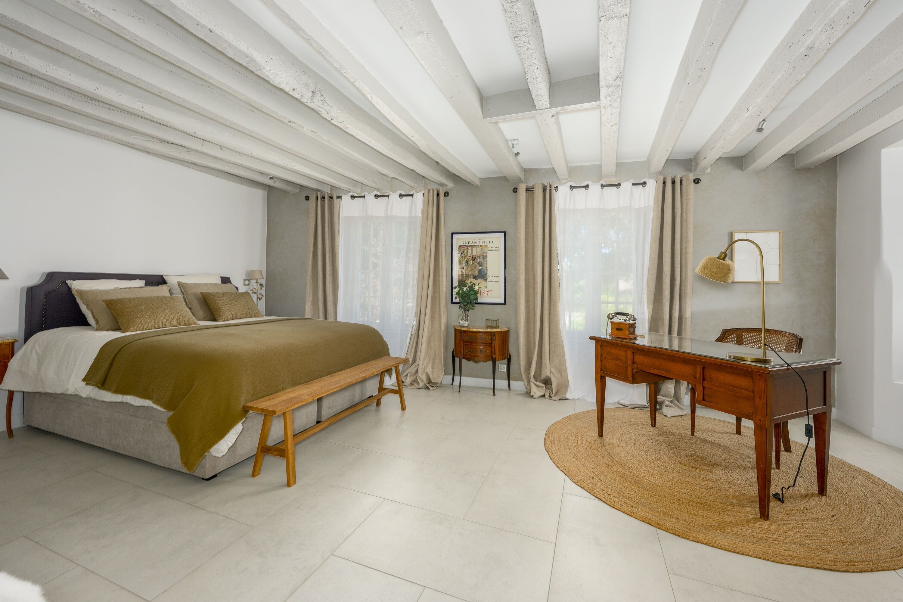 A bedroom with a bed, bedside table, lamp, and a desk with chair.