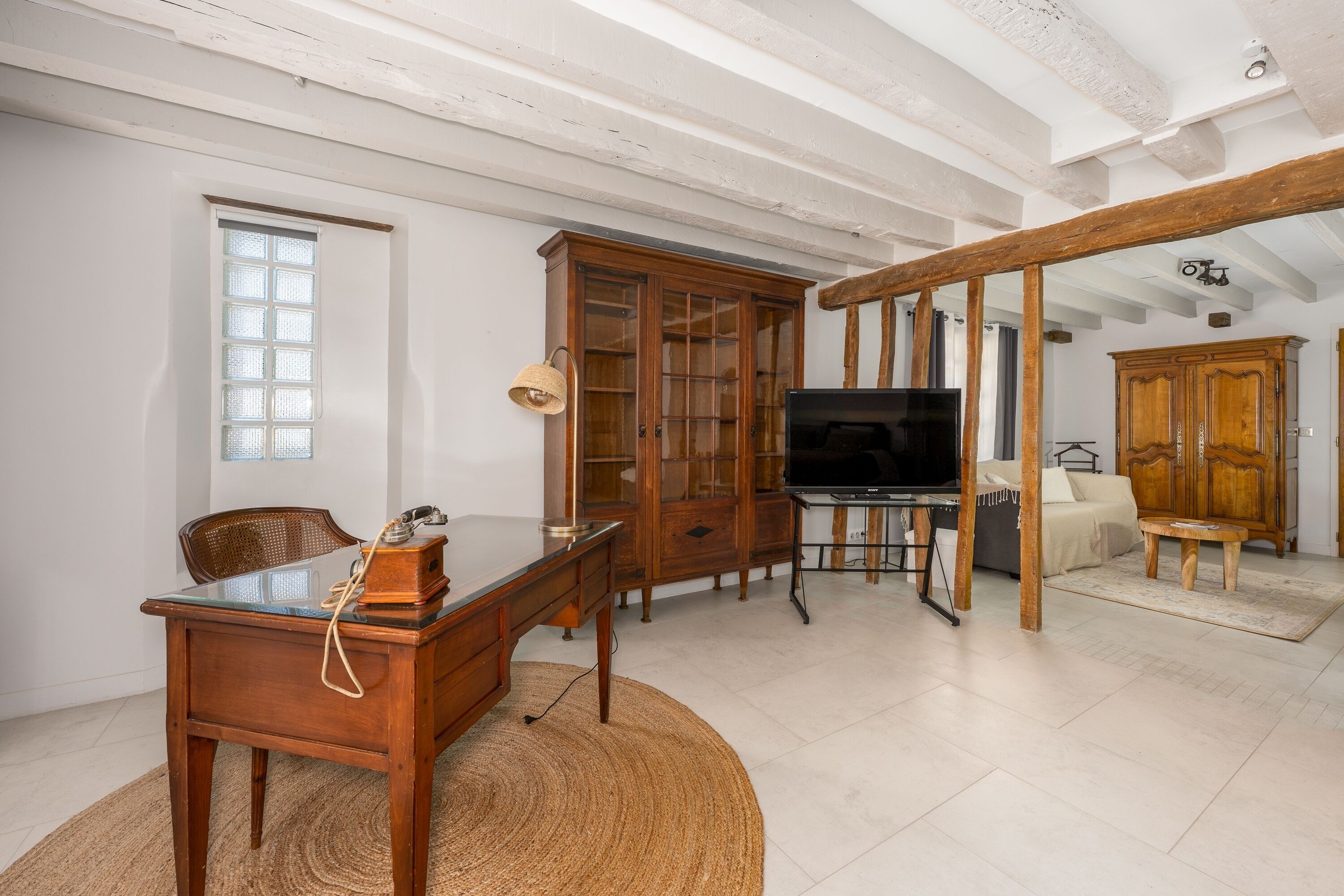 A living room with a wooden desk, a television, and a bookshelf.