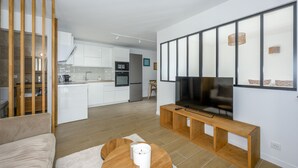 A modern living room with a flat-screen TV, a wooden coffee table, and a sofa. - Le Cèdre - Studio avec Parking (Janvry)