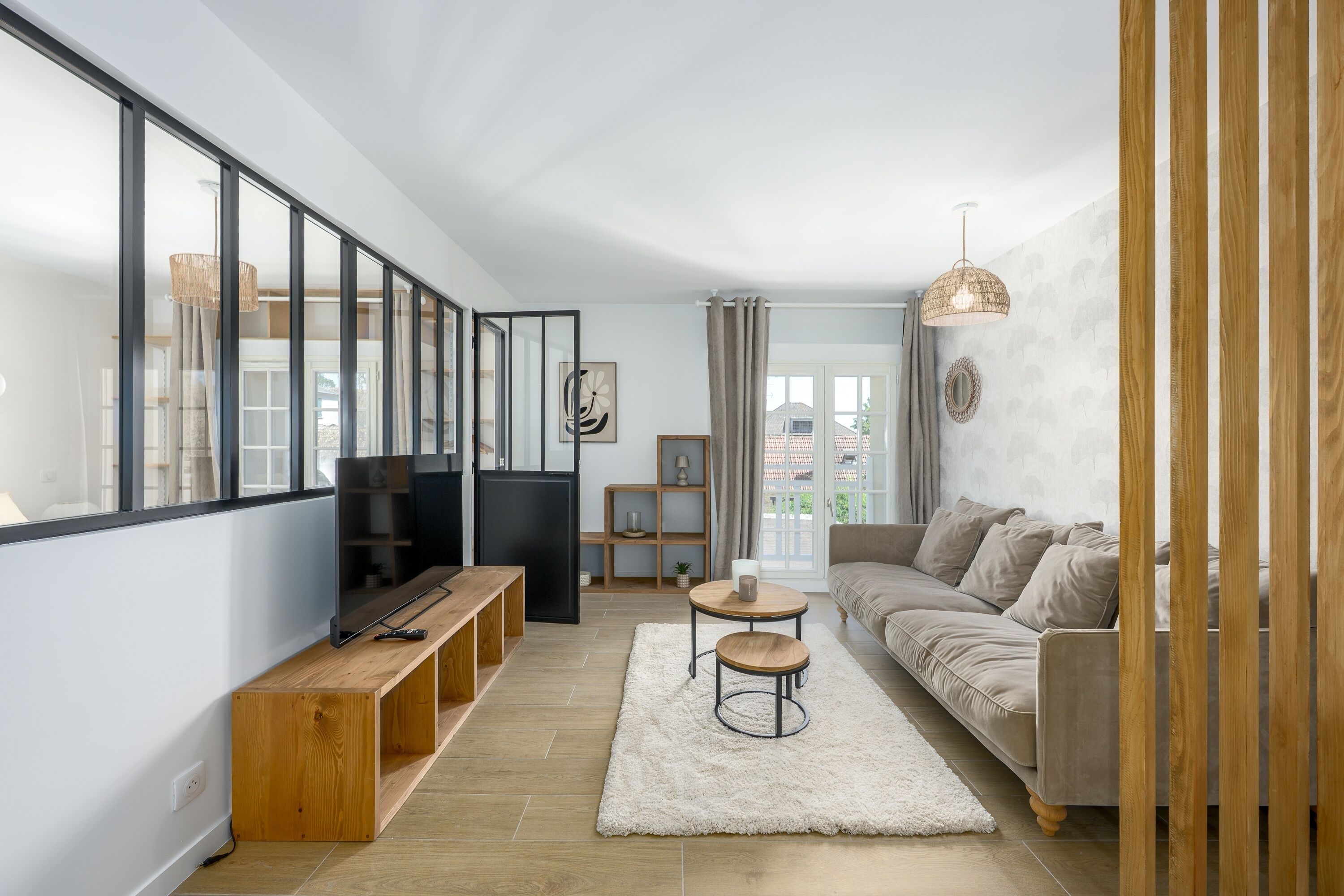 A modern living room with a sofa, a TV, a wooden bench, and a dining table.