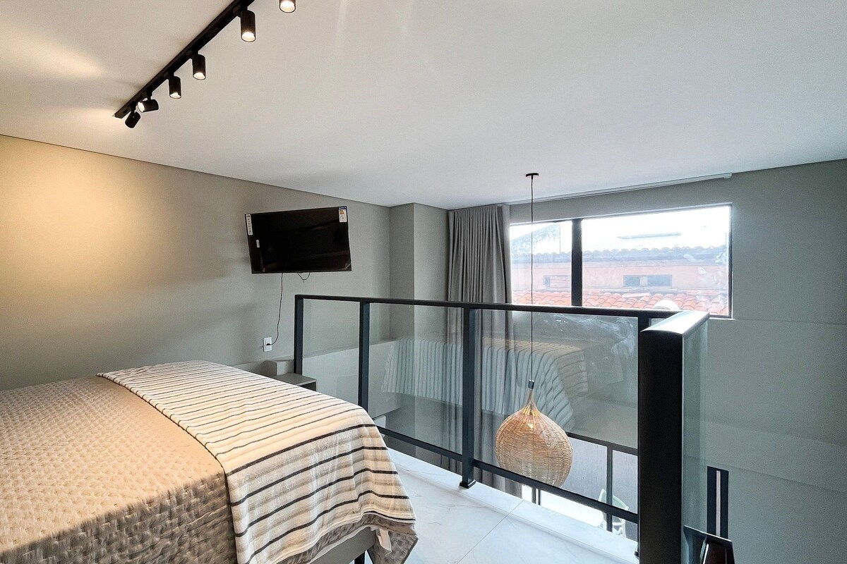 A bedroom with a bed, a television mounted on the wall, and a balcony with a view.