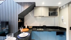 Eine kleine Küche mit Mikrowelle, Spüle und eingebautem Backofen.