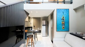 A modern kitchen with a dining area, a refrigerator, and a painting of a boat on the wall. - Smeralda del Mare Residence - Porto de Galinhas (Ipojuca)