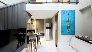 A modern kitchen with a dining area, a refrigerator, and a painting of a boat on the wall. - Smeralda del Mare Residence - Porto de Galinhas (Ipojuca)