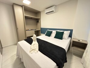 Ein Hotelzimmer mit einem Bett, einem Kleiderschrank, einem Nachttisch und einer Klimaanlage.